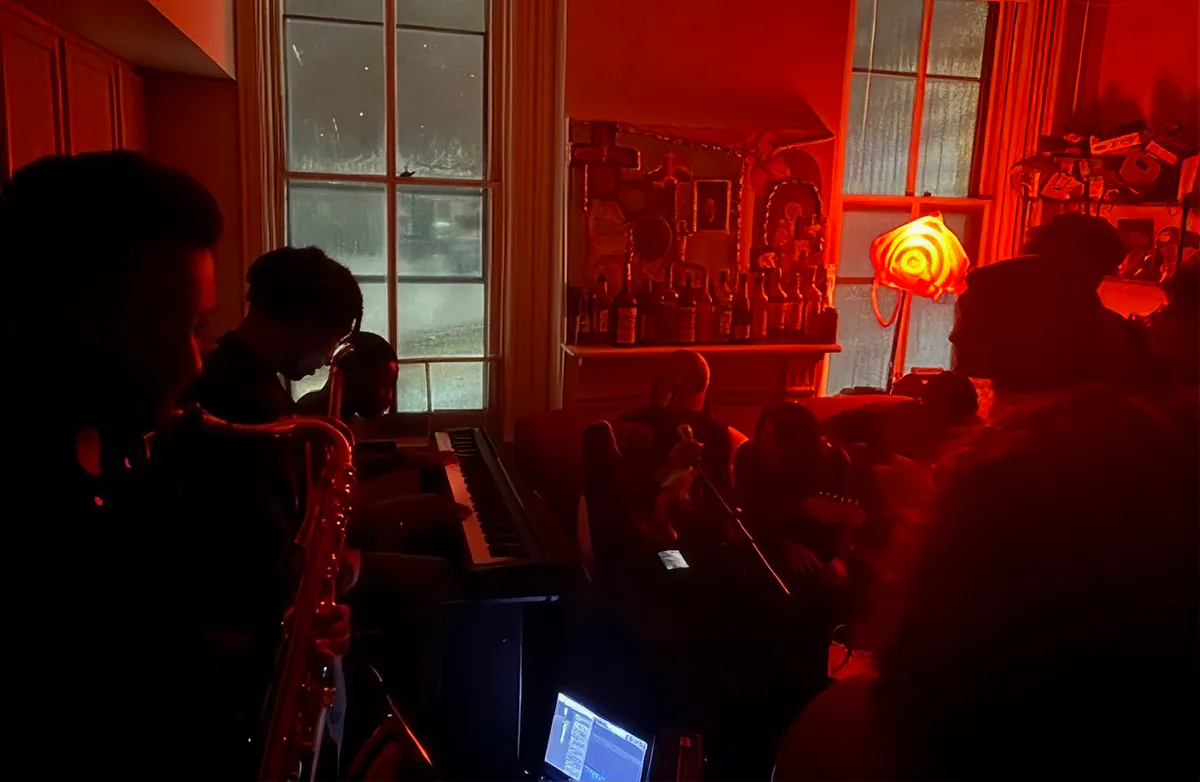A saxophonist and keyboard player in a room washed in red light.